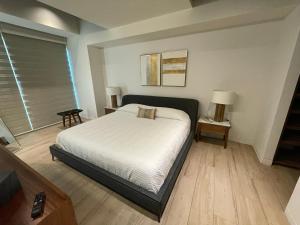 瓜达拉哈拉Apartamento en Lobby33的一间卧室设有床、两张桌子和一扇窗户