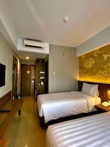 日惹Unisi Hotel Malioboro - Jogja Syariah的酒店客房设有两张床和电视。