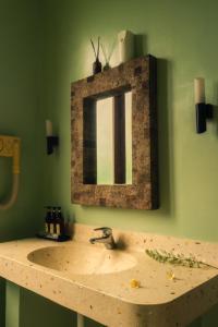 坎古Ecosfera Hotel, Yoga & Spa的浴室水槽和绿色墙壁上的镜子