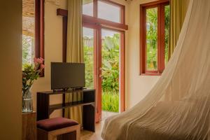 坎古Ecosfera Hotel, Yoga & Spa的一间卧室设有一张床、一台电视和一个窗口。