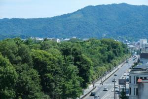 京都RAKURO Kyoto by THE SHARE HOTELS的享有树木林立的街道和山脉的景色