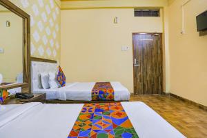 瓦拉纳西FabHotel Shivam Palace的一间酒店客房,设有两张床和一扇门