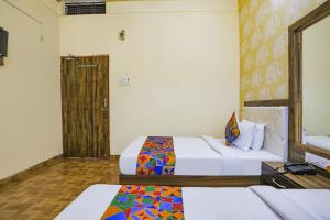 瓦拉纳西FabHotel Shivam Palace的一间酒店客房,设有两张床和一扇门
