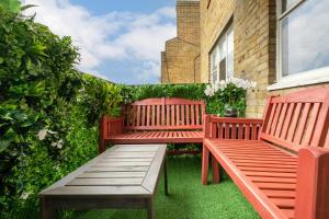 伦敦Luxury 3 Bedrooms Apartment in Central London的两把红色长椅坐在建筑物前面的草上