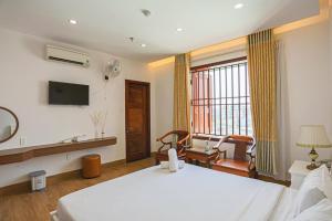 岘港SeaColor Beachstay Danang Hotel by Haviland的一间酒店客房,配有一张床和一台电视