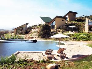 萨兰达Botë Farms Agriturismo的一座房子,设有一座带两把椅子和一把遮阳伞的游泳池