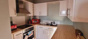 斯旺西Modern and spacious Swansea centre apartment的厨房配有白色橱柜和红色微波炉