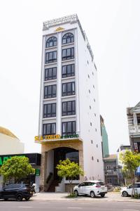 岘港SeaColor Beachstay Danang Hotel by Haviland的一座高大的白色建筑,上面有标志