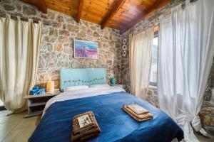 卡梅纳维洛拉Magical view, Villa Asproneri, Kamena Vourla的一间卧室设有蓝色的床和石墙