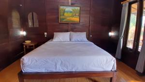塔巴南The Bocah Desa Village的一间卧室配有一张带白色床单的大床