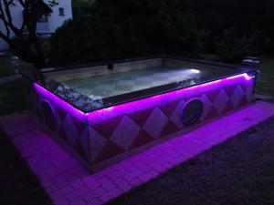 PilisszentivánHill View Holiday House nearby Budapest with AC & Pool的紫色灯火点亮的热水浴池