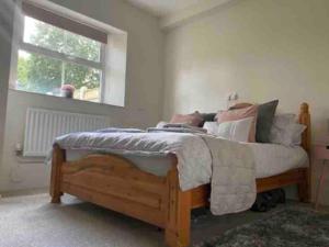 曼斯利SeaBright; one bed apartment with garden and parking的卧室配有带枕头的木床和窗户。