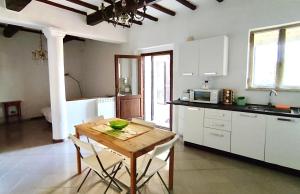 PorronaPoggio alla Pietra 26的厨房配有木桌和白色橱柜。