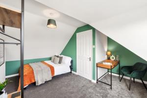 切姆Hidden Gem with Large Driveway, Comfortable Beds, Netflix, and Expansive Garden!的一间卧室拥有绿色和白色的墙壁,配有一张床和一张书桌