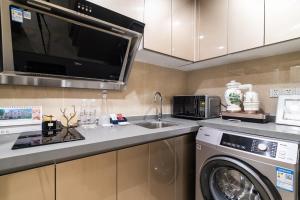广州Cloud Land Apartment 翡翠华庭的厨房配有洗衣机和微波炉。
