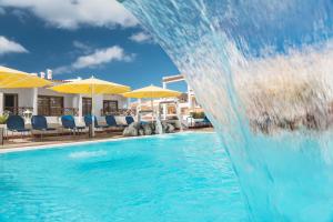 阿罗纳Spa & Sport Hotel Mar y Sol的游泳池内的水滑梯,配有椅子和遮阳伞