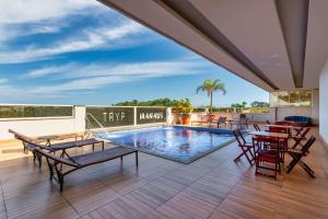 马瑙斯TRYP by Wyndham Manaus的一个带游泳池和桌椅的庭院