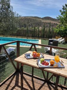 贝莱斯-鲁维奥Casa Los Bartolos的游泳池旁的桌子上摆放着水果和果汁