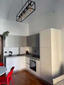 都灵Margarita Apartment Porta Susa Torino的厨房配有白色橱柜和红色椅子的桌子