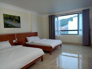 下龙湾Hotel trung hiếu的酒店客房设有两张床和窗户。