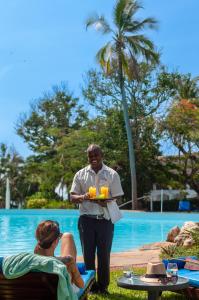 迪亚尼海滩Diamonds Leisure Beach & Golf Resort的持着饮料盘的男人,在游泳池附近