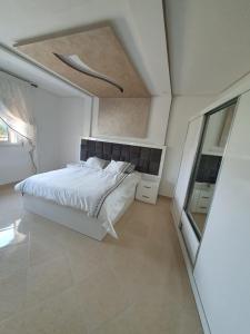 胡塞马Al Hoceima Ajdir Maroc - Maison 5 chambres 10 personnes的卧室配有一张白色大床和镜子