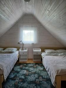 FilipówDomki skowronki的阁楼卧室设有两张床和窗户。