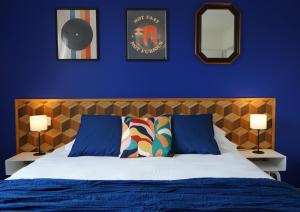 SimandreVilla Casa Mia - BY PRIMO C0NCIERGERIE的一间卧室配有一张带蓝色墙壁的床和两盏灯。