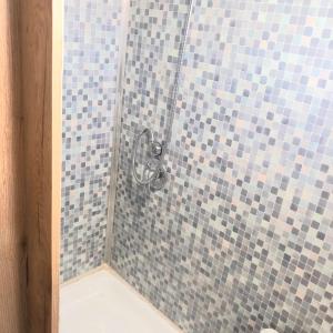 Kefar H̱ananyaלנפוש על גלגלים的浴室设有蓝色和灰色瓷砖淋浴。