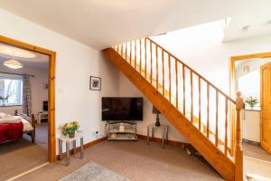 伯恩利Oak Tree Cottage - Pendle - Forest of Bowland的一间带楼梯和电视的客厅