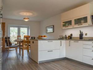 伯恩利Oak Tree Cottage - Pendle - Forest of Bowland的厨房配有白色橱柜和桌椅