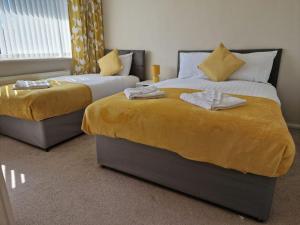 利兹4 beds with links to motorways的一间卧室设有两张带黄床单的床和窗户。