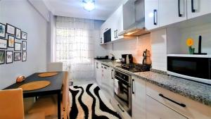 安塔利亚Fully Furnished Stylish Apartment in Antalya的厨房配有白色橱柜、桌子和柜台。