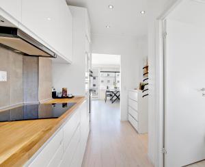 兰讷斯Moderne lejlighed med privat parkering的厨房配有白色橱柜和木地板。
