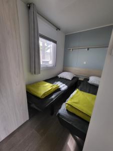 纳博讷普拉日Mobil-home (Clim)- Camping Narbonne-Plage 4* - 019的客房设有两张带黄床单的床和窗户。