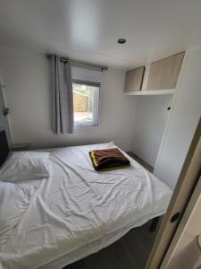纳博讷普拉日Mobil-home (Clim)- Camping Narbonne-Plage 4* - 019的一间小卧室,配有一张白色的床和窗户