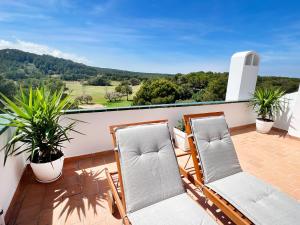 桑帕克Apartamento Atardecer en Menorca Son Parc Vista al campo de golf的美景阳台,配有两把椅子