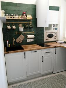 塞格德Hanna apartman的厨房配有白色橱柜和绿色瓷砖