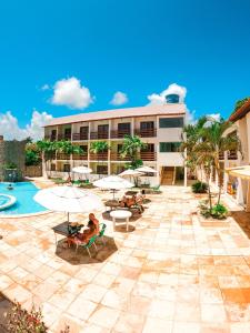 嘎林海斯港Estação do Sol Praia Hotel的一个带游泳池、椅子和遮阳伞的度假村