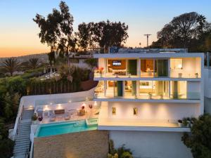 洛杉矶Beverly Grove的一座白色的大房子,背面有日落