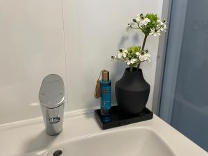 帕绍Tinyhouse mit Alpen- Stadt- und Poolblick , WLAN的浴室水槽,花瓶里放着鲜花,配有牙刷