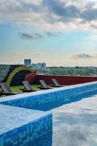 梅里达Hotel Kavia Premium - Paseo Montejo的游泳池旁的一排椅子