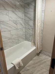 鸽子谷熊山酒店的浴室铺有大理石瓷砖,配有白色浴缸。