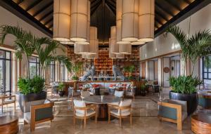 普拉亚卡门Fairmont Mayakoba Riviera Maya - All Inclusive的一间设有桌椅的餐厅,种植了植物