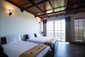 努沃勒埃利耶Terrabella - Nuwara Eliya的一间卧室设有两张床和大窗户