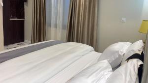 杜阿拉Suna' a Home Bonapriso的一张带白色床单和枕头的床,靠窗