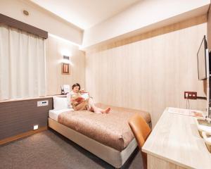 北九州小仓站瑞丽芙酒店的坐在酒店房间床上的女人