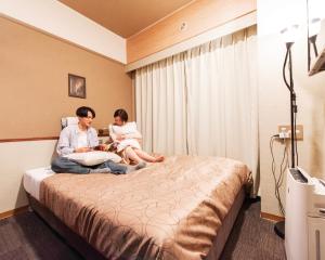 北九州小仓站瑞丽芙酒店的坐在酒店房间床上的男女