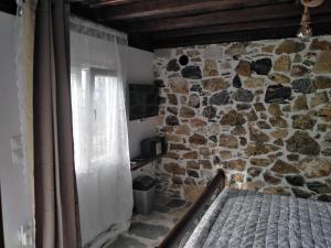 霍里顿Ελαιώνας - Solar Energy House的一间卧室设有石墙、一张床和一个窗口