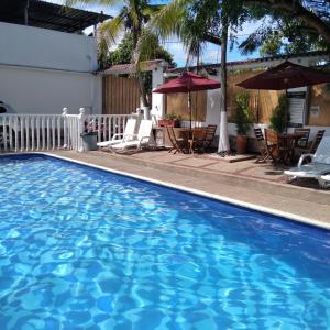 梅尔加HOTEL MACEO MELGAR的游泳池,酒店配有椅子和遮阳伞